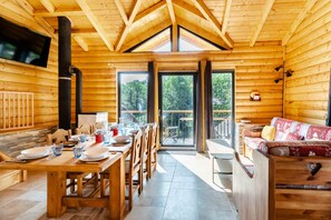 A wooden cabin with a dining area, a sofa, and a large window. - Spacious Family Chalet – Courchevel / Brides-les-Bains with Mountain Views (Courchevel)
