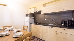 Een kleine keuken met houten kastjes, een zwart aanrecht, een magnetron, een fornuis en een spoelbak.
