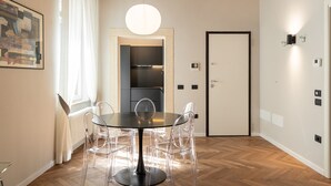 A modern dining area with a round table, clear chairs, and a pendant light. - Residenza Marconi 1 (Verona)