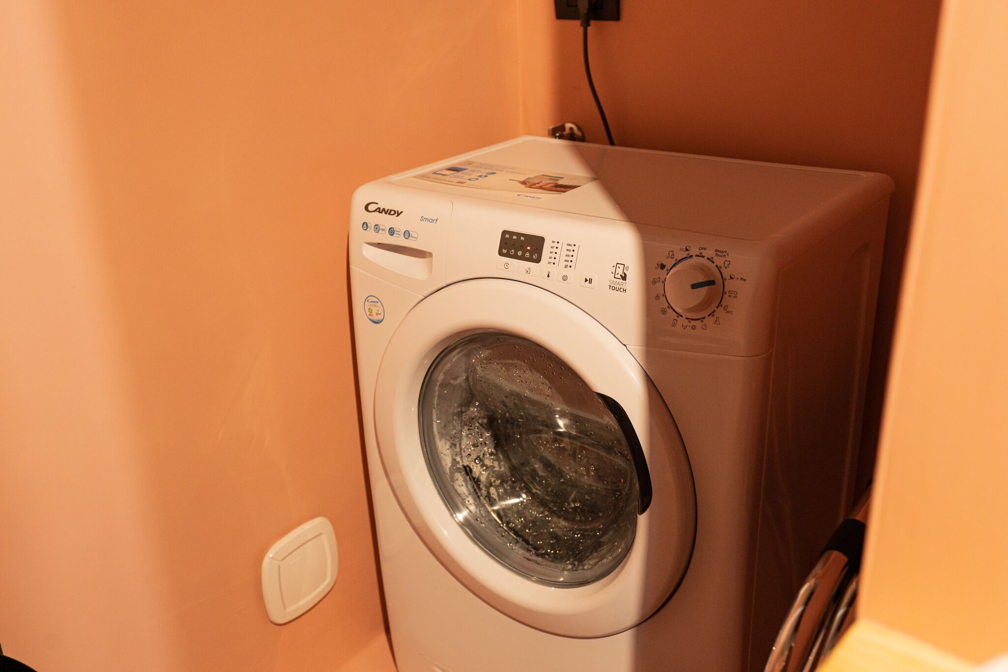 A front-loading washing machine with a control panel, a digital display, and a dial for temperature settings.