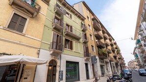 A multi-story building with balconies, a storefront with a large window, and parked motorcycles. - Residenza Marconi 1 (Verona)