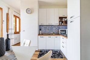 A compact kitchen with white cabinets, a microwave, and a blue patterned backsplash.