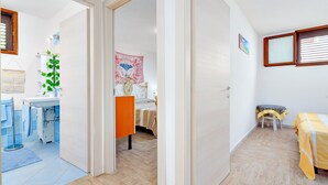 A room with a bed, a chair, a small table, a window, and a door leading to another room. - Holiday Apartment "Caterina" with Shared Terrace & Wi-Fi (Siniscola)