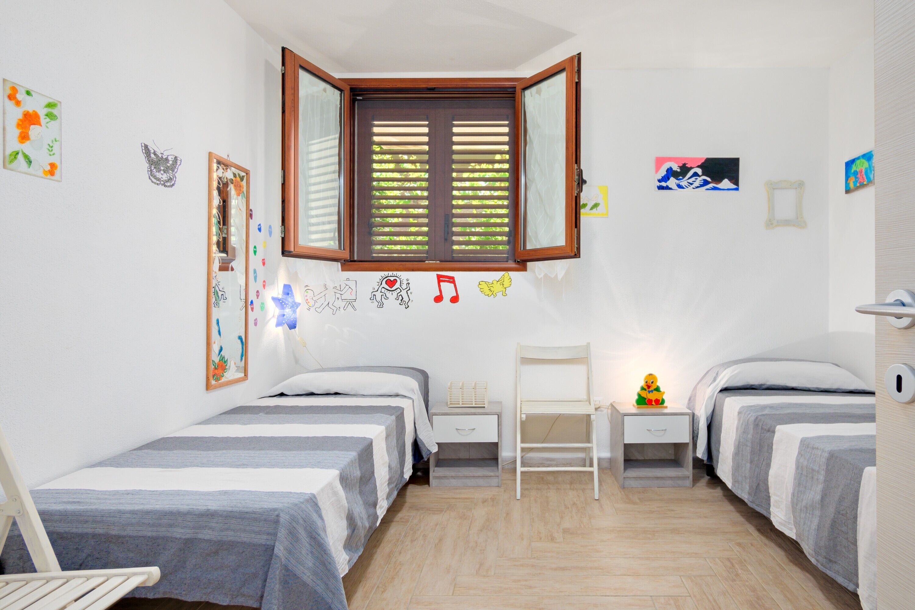 Una camera da letto con due letti, una finestra, una scrivania e decorazioni alle pareti.