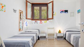 Una camera da letto con due letti, una finestra, una scrivania e decorazioni alle pareti.