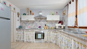 A kitchen with a refrigerator, microwave, oven, and sink. - Holiday Apartment "Caterina" with Shared Terrace & Wi-Fi (Siniscola)