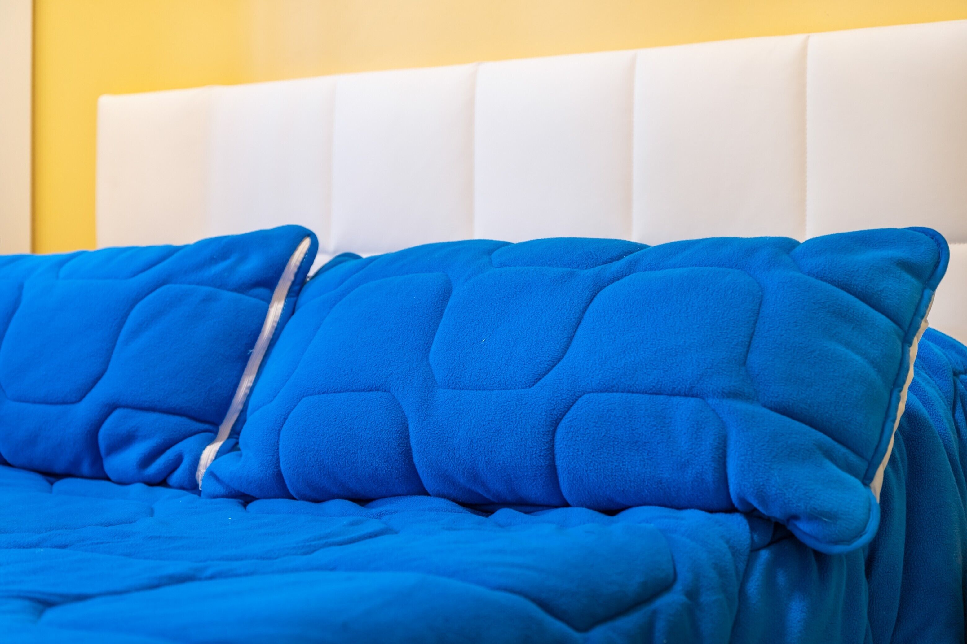 Una cama con cabecera blanca y ropa de cama azul.