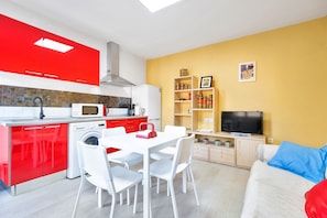 A modern kitchen with red cabinets, a dining table with chairs, a TV, and a sofa with a red pillow. - Villa 'Maria Dependance' with Private Pool, Wi-Fi and Air Conditioning (TORREVIEJA)