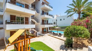 A multi-story building with balconies, a pool, and a children's play area. - "Gran Sol Family 1" Apartment with Shared Pool, Wi-Fi, and Air Conditioning (Tourist Tax Included) (Felanitx)