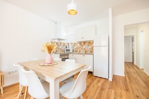 Une cuisine moderne avec des meubles blancs, une table à manger en bois et des chaises blanches.