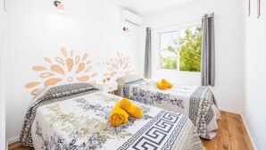 Una habitación de hotel con dos camas, una ventana con vistas, un equipo de aire acondicionado y un adorno en la pared.