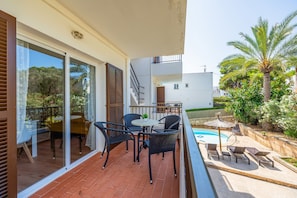 Un balcon avec une piscine, du mobilier d’extérieur et une vue sur la verdure environnante.