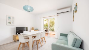 Uma sala de estar moderna com área de jantar, sofá, televisão e varanda com vista.