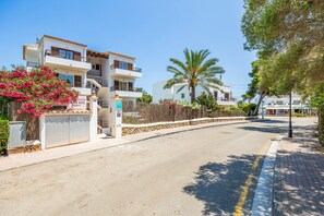 A residential street with houses, a palm tree, and a sign for 'GRAN SOL FAMILY'.
