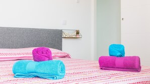 Een bed met een beddekleed met patroon, een grijs hoofdeinde en een decoratief object aan de muur.