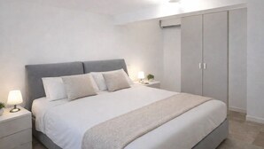 A bedroom with a bed, bedside tables, a lamp, a plant, and a wardrobe.