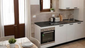A modern kitchen with white cabinets, a black countertop, and a window with curtains.