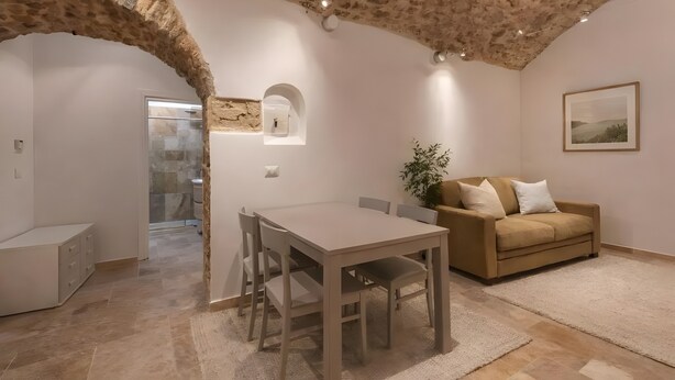 Amplia sala de estar con techo de piedra, un sofá color beige, una mesa de comedor y un cuadro en la pared.