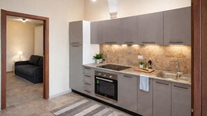 A modern kitchen with grey cabinets, a built-in oven, a sink, and a countertop with a plant and a bottle.