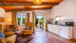 A cozy living room with a sofa, armchair, and a small table. There's a kitchen area with a microwave and a refrigerator. - Apartment “Junior Suite Adults Only Mallorca” with Mountain View, Shared Pool & Wi-Fi (Manacor)