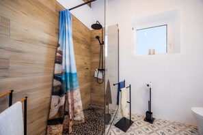 Een douche met een houten wand, een raam en een betegelde vloer.