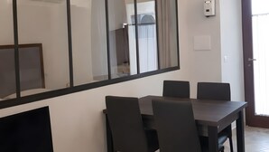 A dining area with a curved glass partition, a flat-screen TV, and a modern table with chairs. - Apartment 'Cafuorchie - Arco Pronti' with Mountain View, Wi-Fi and Air Conditioning (Sant'Agata di Puglia)