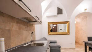 A modern kitchen with a built-in stove, a sink, and a dining area with a table and chairs. - Apartment 'Cafuorchie - Arco Pronti' with Mountain View, Wi-Fi and Air Conditioning (Sant'Agata di Puglia)