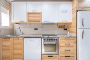 A compact kitchen with white cabinets, a built-in dishwasher, an oven, and a refrigerator. - Apartment 'La Gimena ' with Balcony and Air Conditioning (Orihuela)