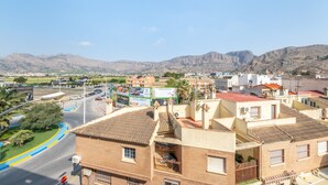 Un quartier résidentiel avec des immeubles, une route et des montagnes en arrière-plan.