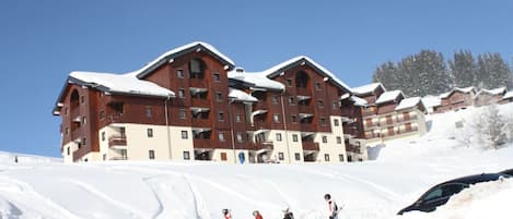 Een meerhoog hotel met een skipiste op de voorgrond.