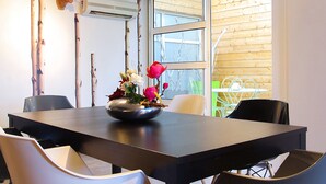 Un coin repas avec une table en bois foncé, des chaises blanches et un vase rempli de fleurs.
