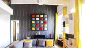 Un salon moderne avec un canapé d’angle, un luminaire fixé au mur et un panneau décoratif mural.