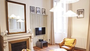 En stue med pejs, fjernsyn, sofa, sofabord og et stort spejl.