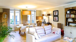 A cozy living room with a white sofa, a wooden cabinet, and a dining area with a table and chairs.