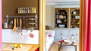 A kitchen with hanging utensils, a fruit bowl, and a coffee machine.
