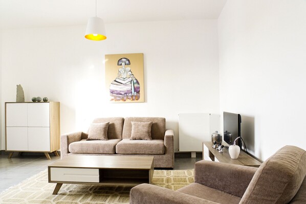 A modern living room with a sofa, a coffee table, a TV, and a painting on the wall. - Cheverus - Centre / 1 chambre avec ascenseur (Burdeos)