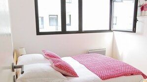 A single bed with white and red bedding, a bedside lamp, and a window with blinds. - Belfort - 2 chambres / Avec ascenseur et Parking (Burdeos)