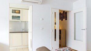 A compact living space with a kitchenette, a sofa with a patterned cushion, and a door leading to a dining area. - Belfort - 2 chambres / Avec ascenseur et Parking (Burdeos)