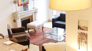 A living room with a fireplace, a sofa, a glass coffee table, and a dining area with chairs and a table. - Condillac - Localisation exceptionnelle avec ascen (Burdeos)