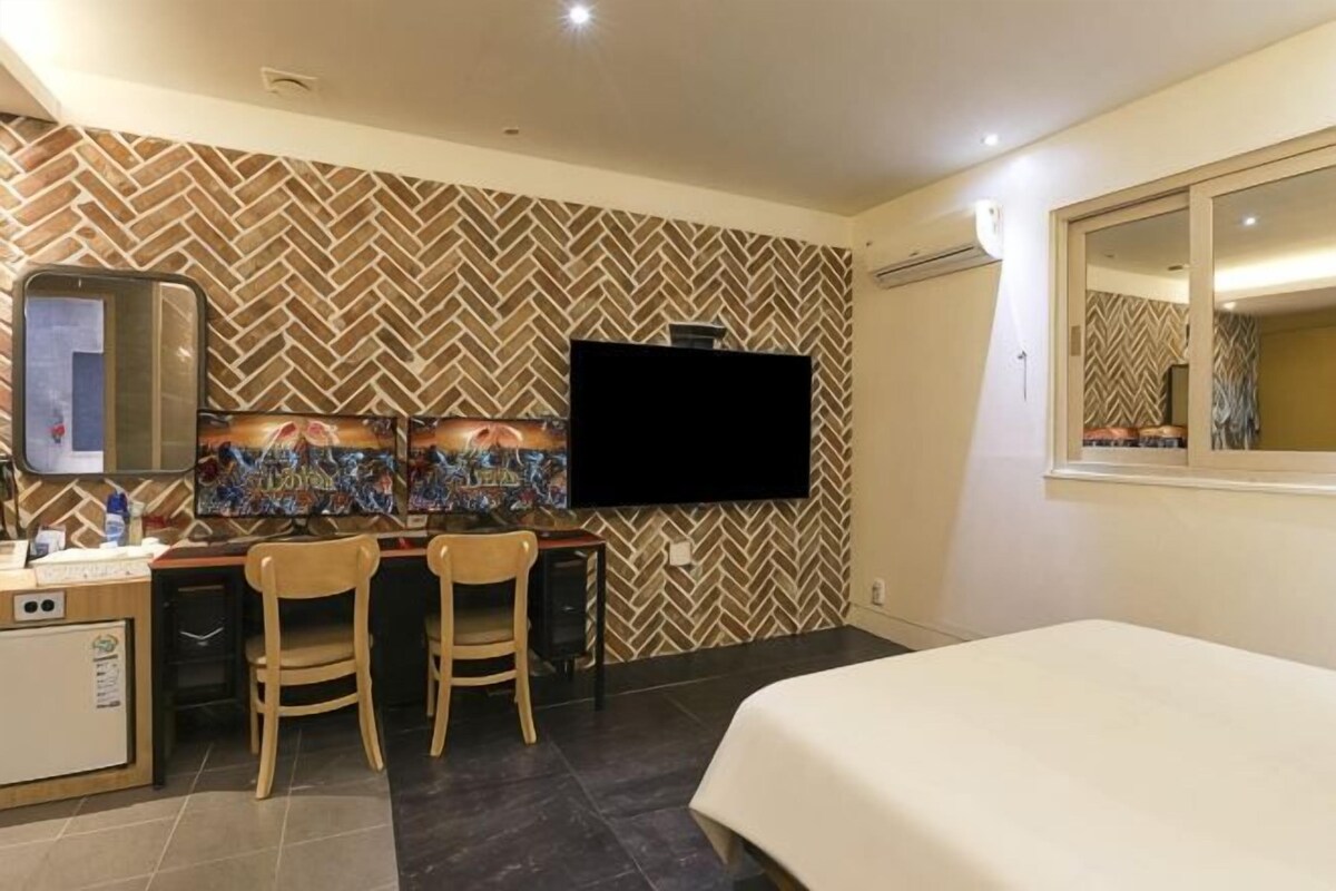 Une chambre d’hôtel comprenant un lit, un bureau avec deux chaises, une télévision et un minibar.