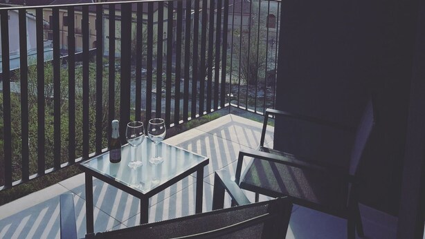 A balcony with a table and chairs, overlooking a cityscape with mountains in the distance. - TaMo Lovely apartment (Fisciano)