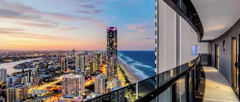 A high-rise building with a view of a beach and cityscape.
