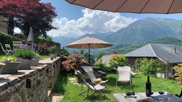A patio with a table set for dining, surrounded by potted plants and a view of mountains. - Eco-friendly apartment in 15th century building, heart of Conflans (Albertville)