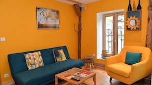 A living room with a blue sofa, a yellow armchair, and a coffee table. - Eco-friendly apartment in 15th century building, heart of Conflans (Albertville)