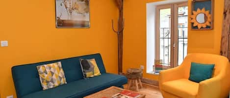 A living room with a blue sofa, a yellow armchair, and a coffee table.