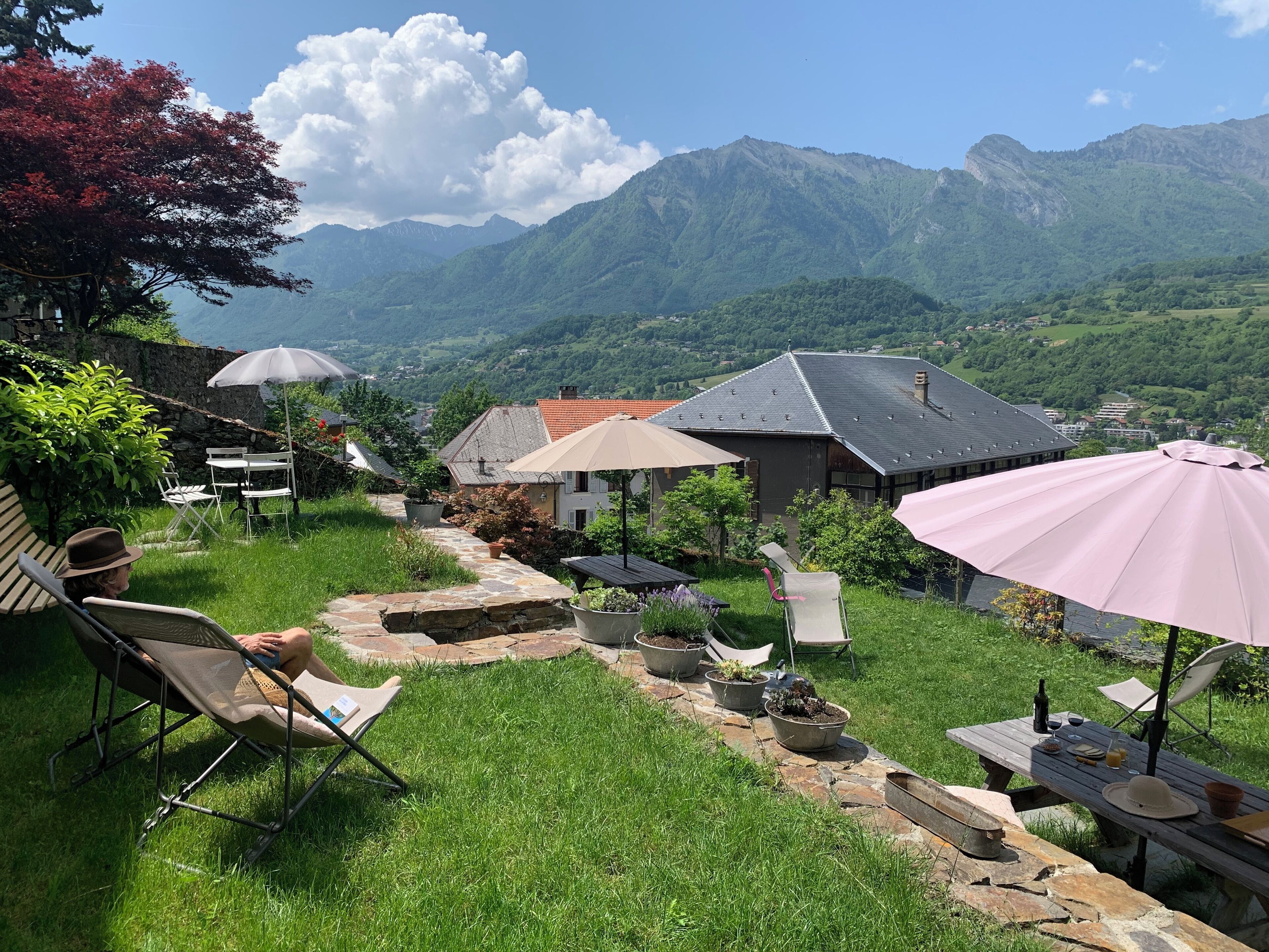 A patio area with outdoor furniture, umbrellas, and a view of mountains.