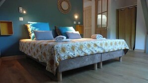 A double bed with a floral bedspread, two pillows, and a wall-mounted light fixture. - Eco-friendly apartment in 15th century building, heart of Conflans (Albertville)