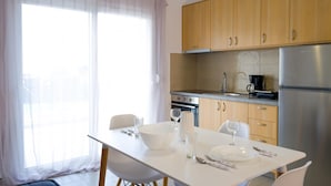 Una cocina moderna con armarios de madera, un refrigerador de acero inoxidable y una mesa para dos comensales.