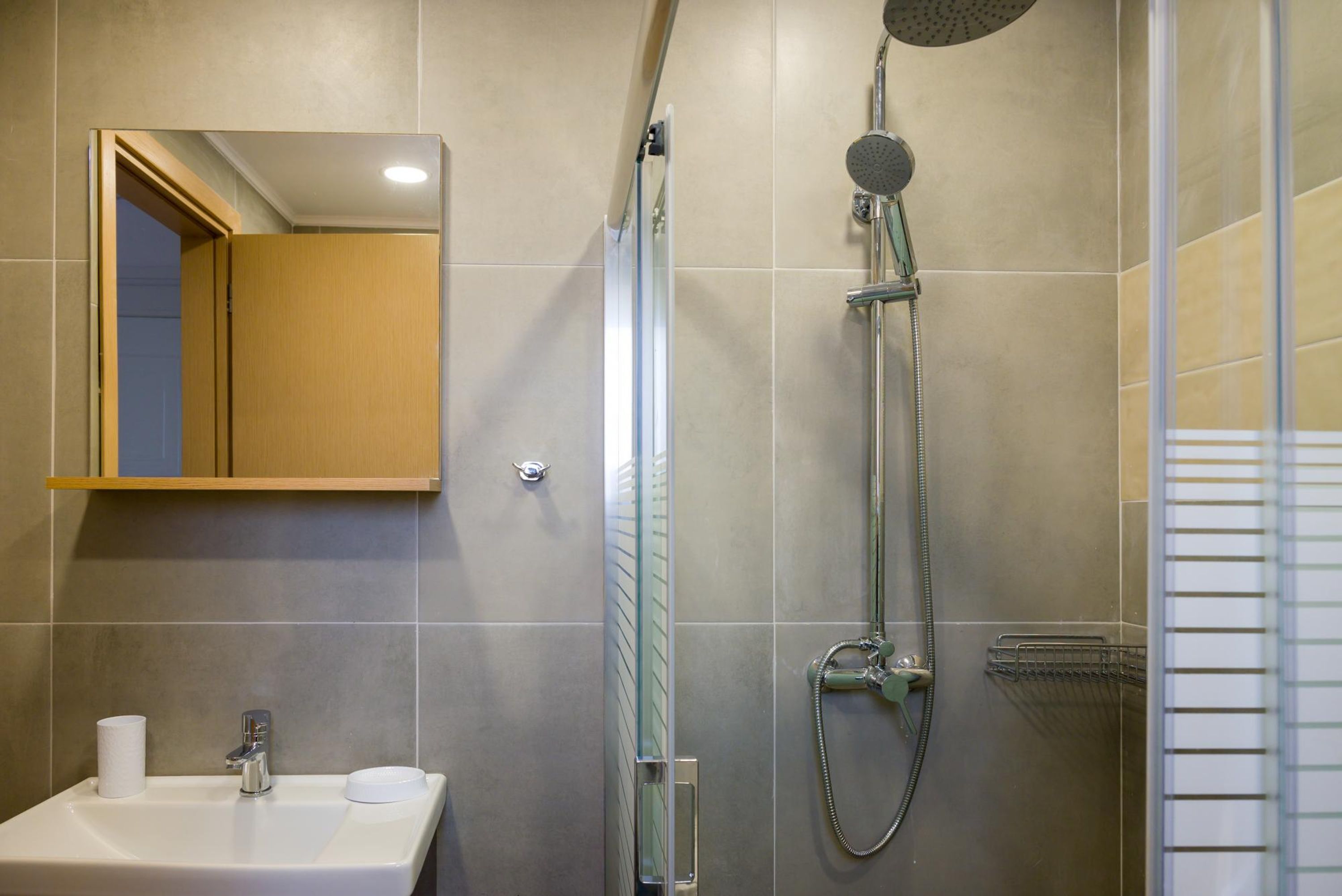 A modern bathroom with a sink, mirror, and shower.