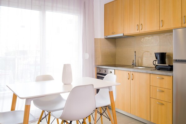 A modern kitchen with wooden cabinets, a white countertop, and a stainless steel refrigerator.